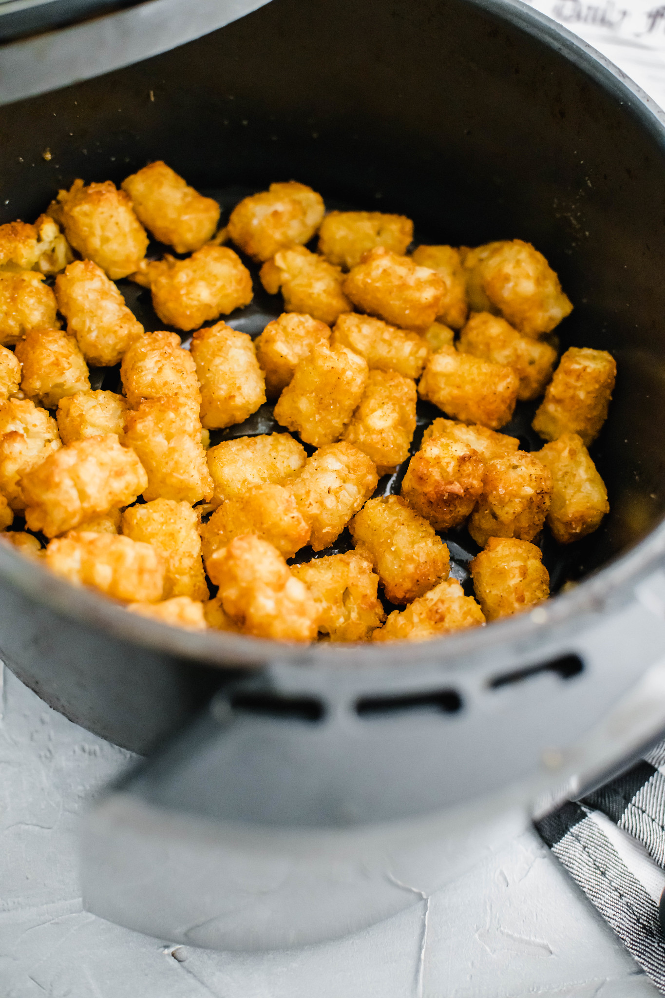 Tater tots in the air fryer basket.