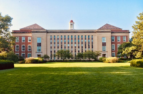 A large red and white building on a college campus sits behind a field of grass - Should I Defer Admission or Take a Leave of Absence?