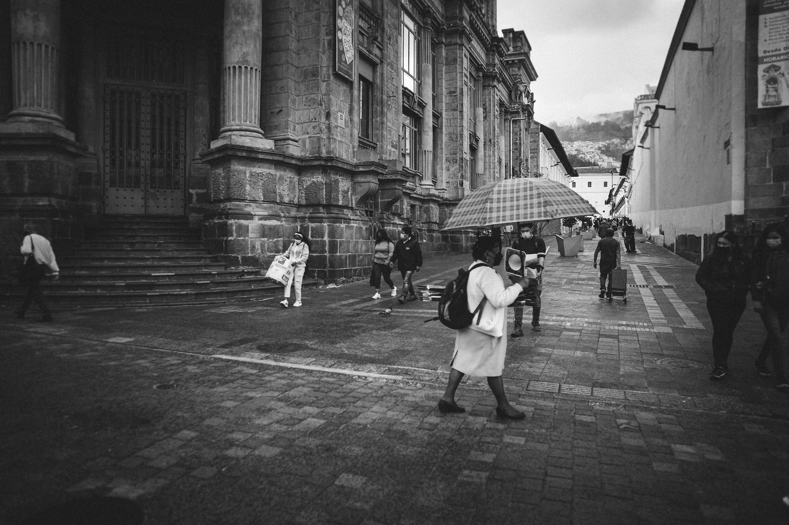 Instantes en Quito - Señora con sombrilla sobre calle empedrada
