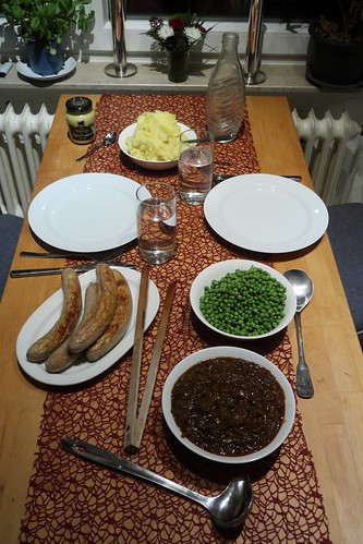 Bratwurst mit Kartoffelstampf, Zwiebelsoße und Erbsen (Tischbild)