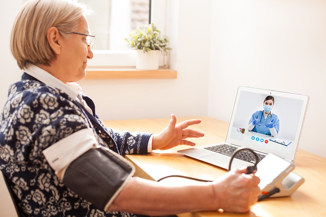 Elderly senior retired woman using sphygmomanometer blood pressure monitor to measure heart rate pulse