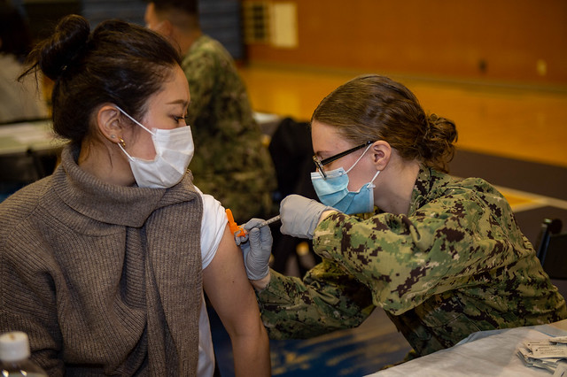 Hospital Corpsman 3rd Class Courtney Minchew administers a COVID-19 vaccination booster to a Japanese base employee at Fleet Activities Yokosuka.