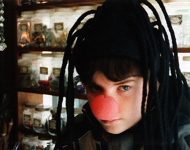 My older son in the Liberty Crafts store after putting on fake dreadlocks and a styrofoam nose. This was a small stop with dozens of jars holding fascinating little toys. Nyack NY. March 2004.