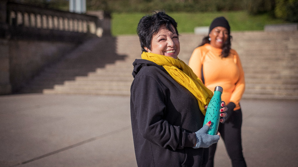 Two older women exercising outside. 
