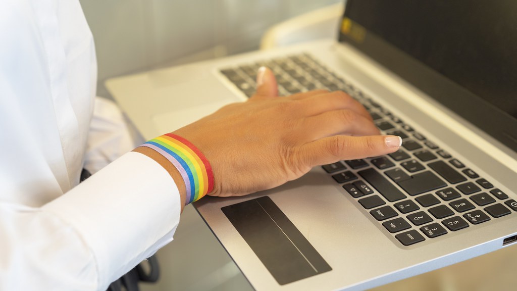 Woman working on a laptop wearing a rainbow wristband
