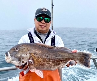 Man on a boat holding a large tautog he caught