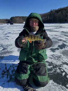 Man on iced-over water holding a yellow perch