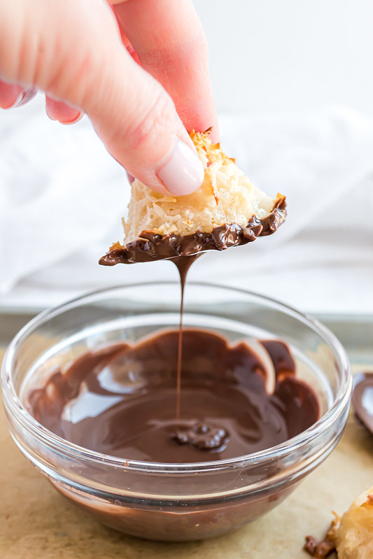 Coconut macaroon being dipped in a bowl of chocolate