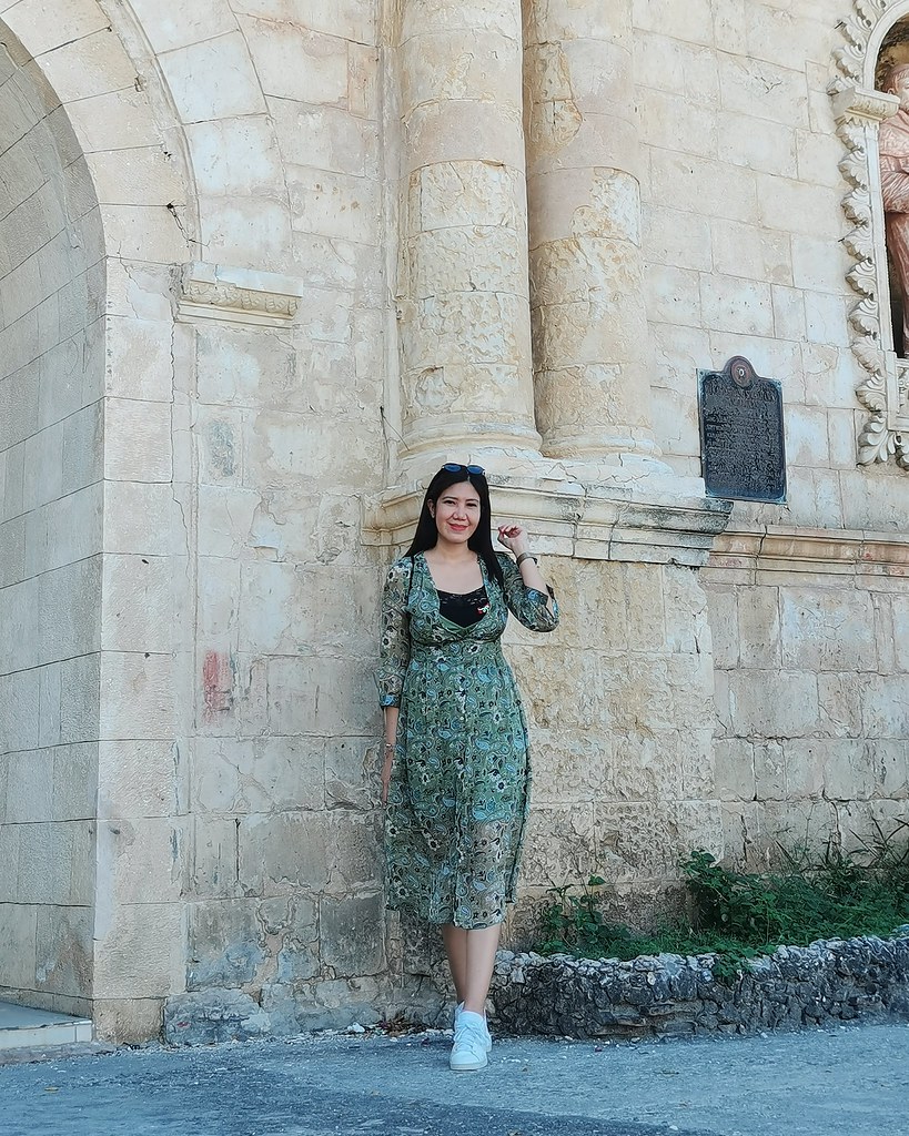 A photo of woman in green dress in front of church
