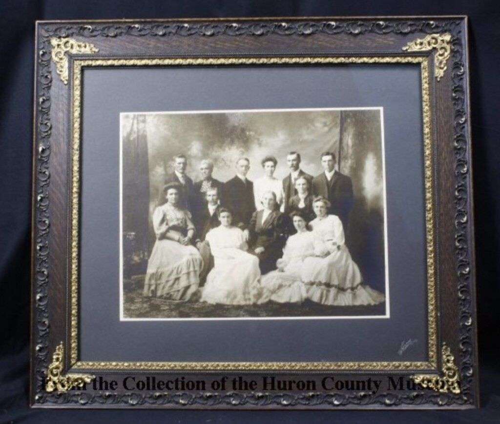 This framed black and white formal studio photograph of the Armstrong-Campbell Family was taken about 1904 by photographer, N.B. Henry, Clinton, ON.