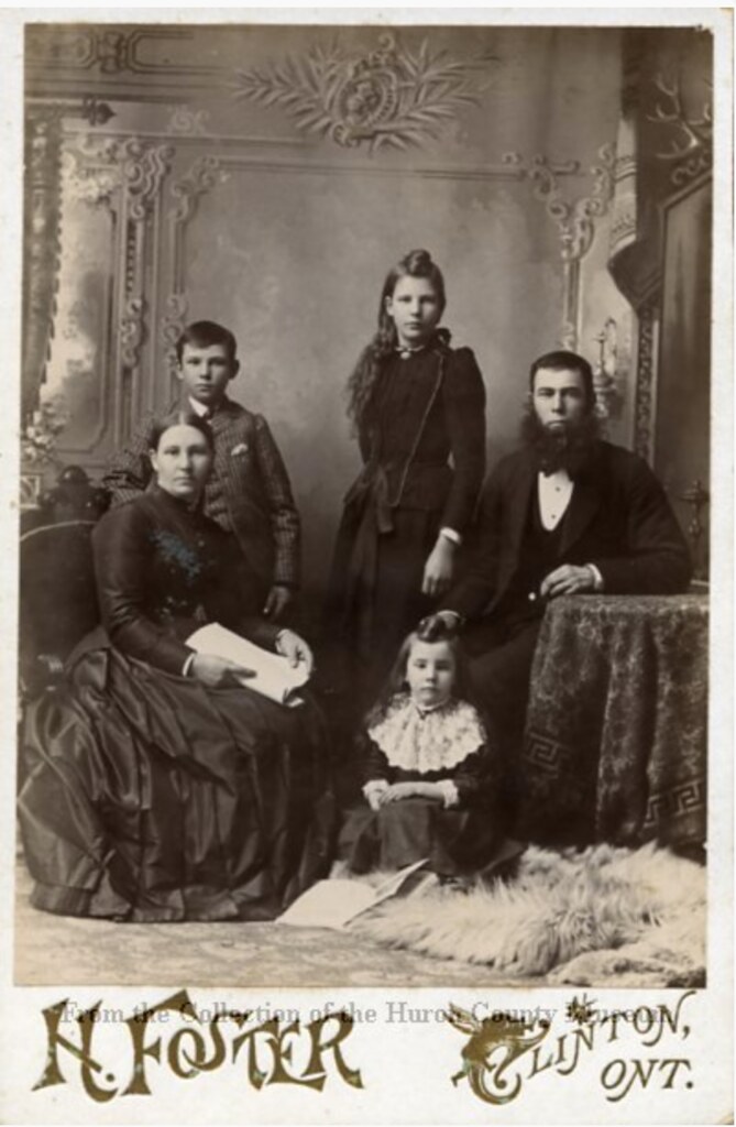 This black and white photograph of five people was taken in the 1880s at the H. Foster Studio in Clinton, ON. The photograph is printed on thick cardstock with the studio title along the bottom.
