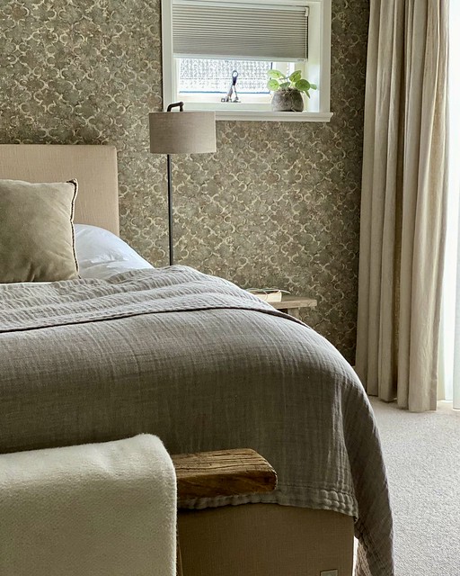 Slaapkamer behang met patroon taupe sprei houten bankje achter bed met plaid