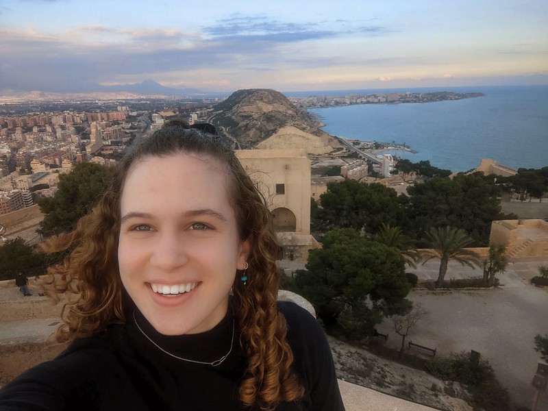 Selfie of Claire withe the city, mountains and ocean of Alicante behind her.