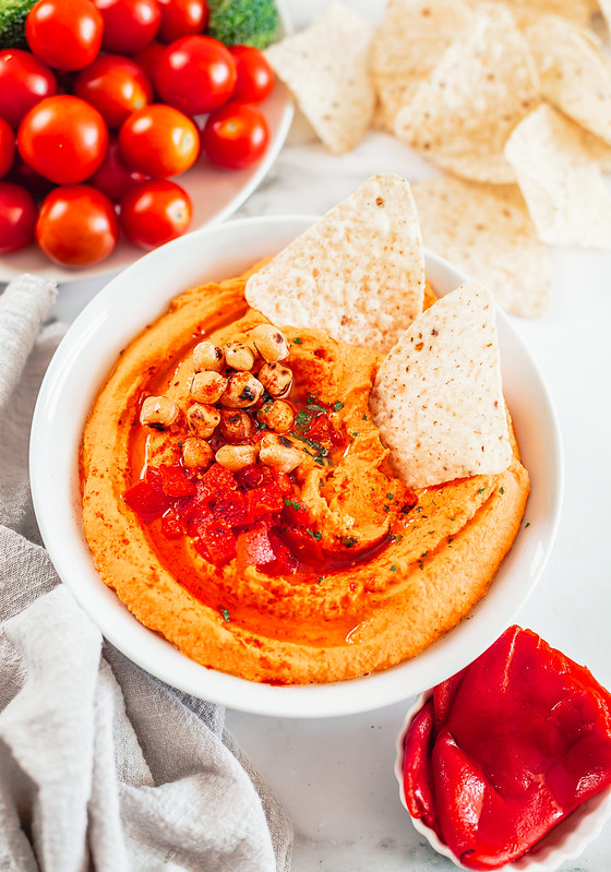 Bowl of roasted red pepper hummus with tortilla chips