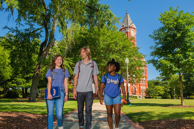 Three Auburn students walking outdoors on the university’s campus.