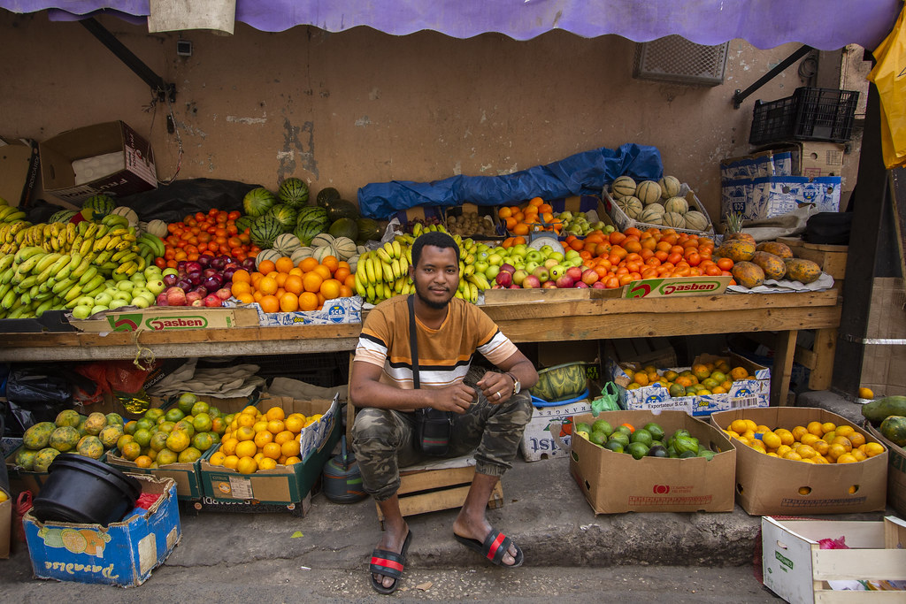 Fruit vendor Mohamed Ba sitting with his merchandise