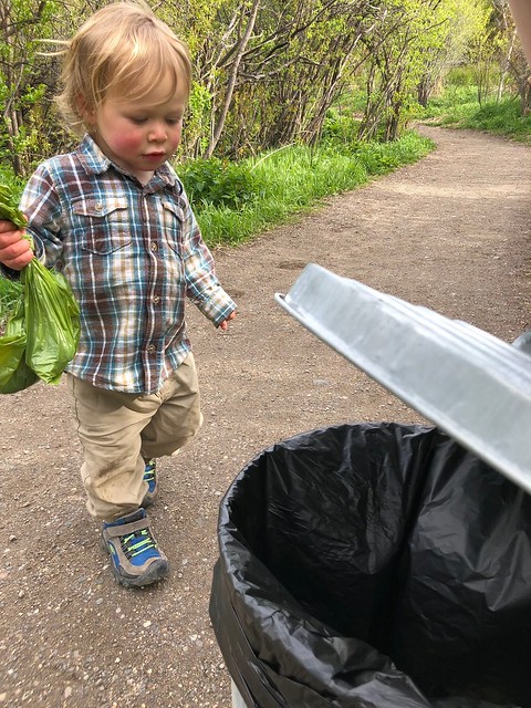 A young child carrying garbage to a trash can