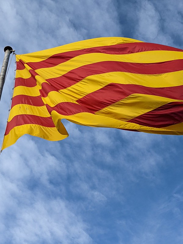 Red and yellow striped flag of Catalunya against the blue sky
