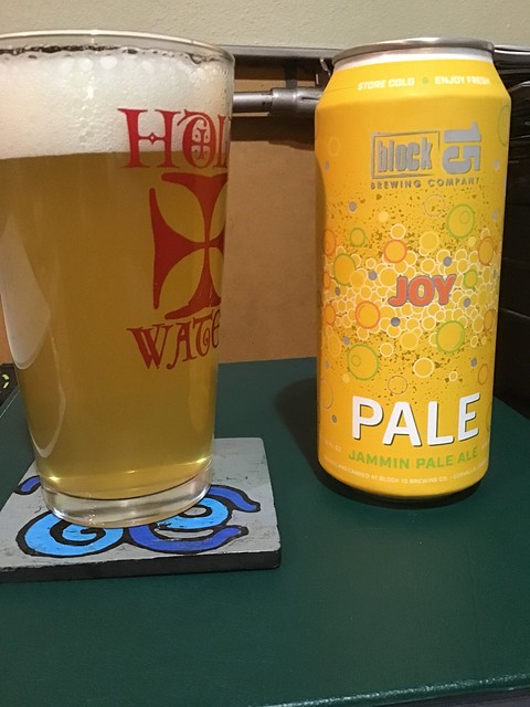 Block 15's Joy pale ale, in glass on desk, next to a can of same