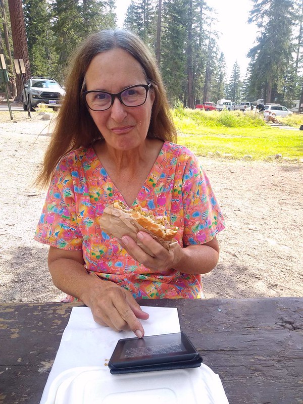 Vicki happily eating a veggie burger and reading her kindle at Reds Meadow Resort