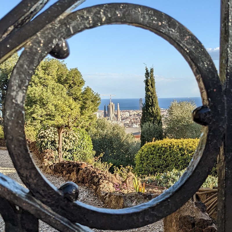 Looking at the Sagrada Familia from Parc Guell, framed by the ring of an iron gate