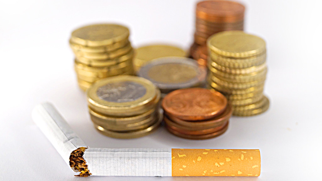 Broken cigarette with pile of coins