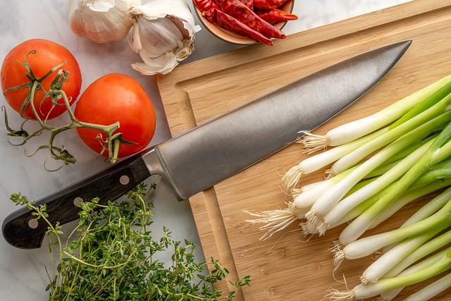 Knife on cutting board with onions tomatoes and spices