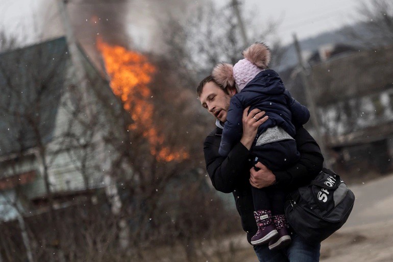 一名男子抱著女孩逃離被轟炸的基輔。（圖片來源：Al Jazeera）