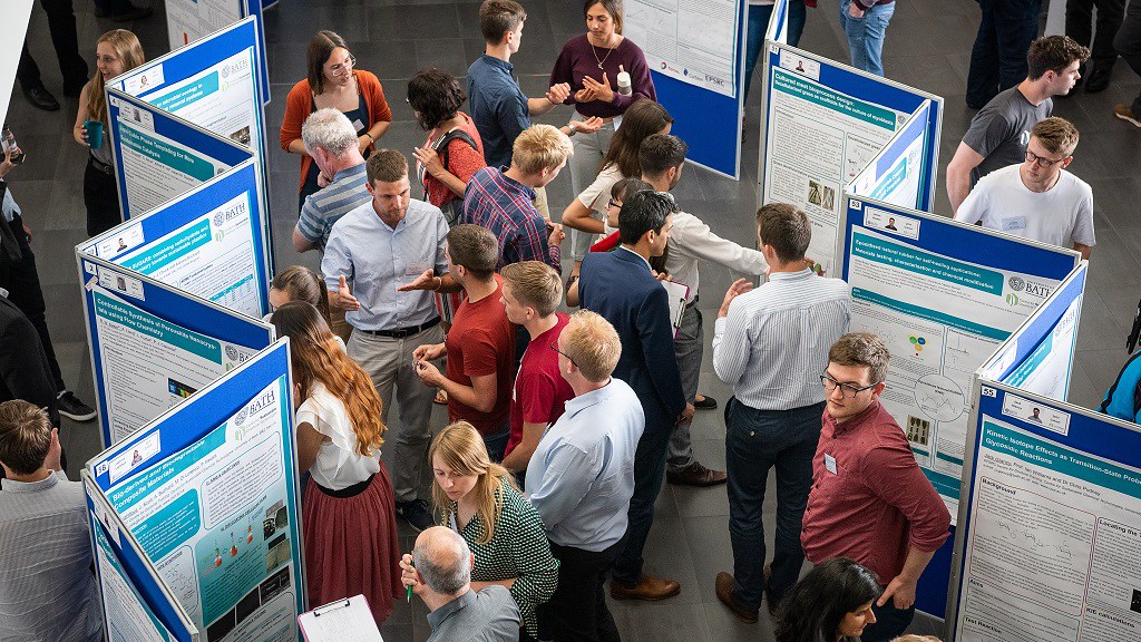 A group of researchers networking around poster boards 