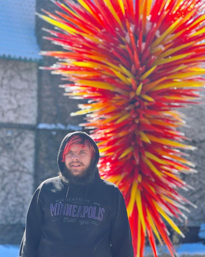 My son standing in front of a sunlit Chihuly piece called The Ellipse at Denver Botanic Gardens