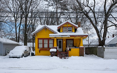 Oh great a Craftsman-style bungalow from 1925, yellow-orange with dark red trim, with tapered columns on its porch, with gabled dormer, with icicles.
