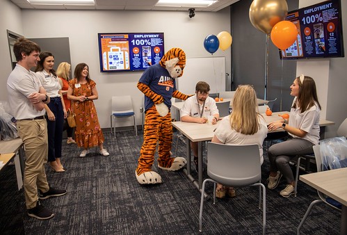 Aubie in nest with students, staff
