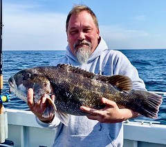  Photo of man on a boat holding a tautog