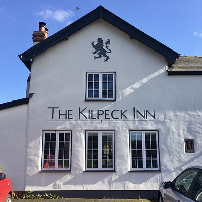 Photo of The Kilpeck Inn, an old white-painted pub with its name painted in capitals on one gable end
