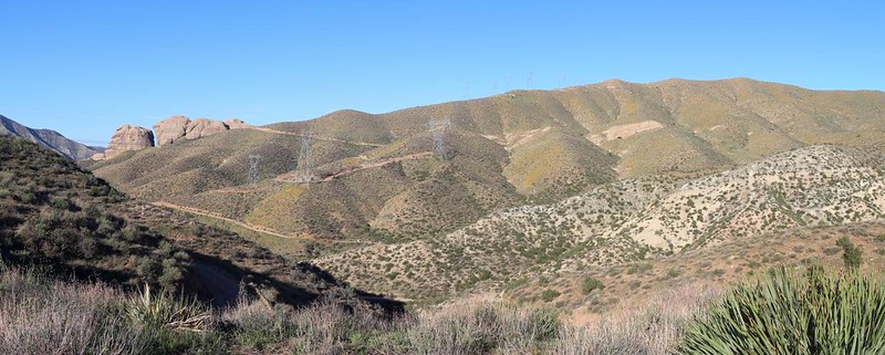 Panorama view over Bobcat Canyon, with Three Sisters Rock on the far left, and a small cave on the right