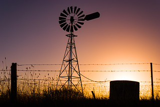 Classic Australian windmill on farmland silhouetted at sunset