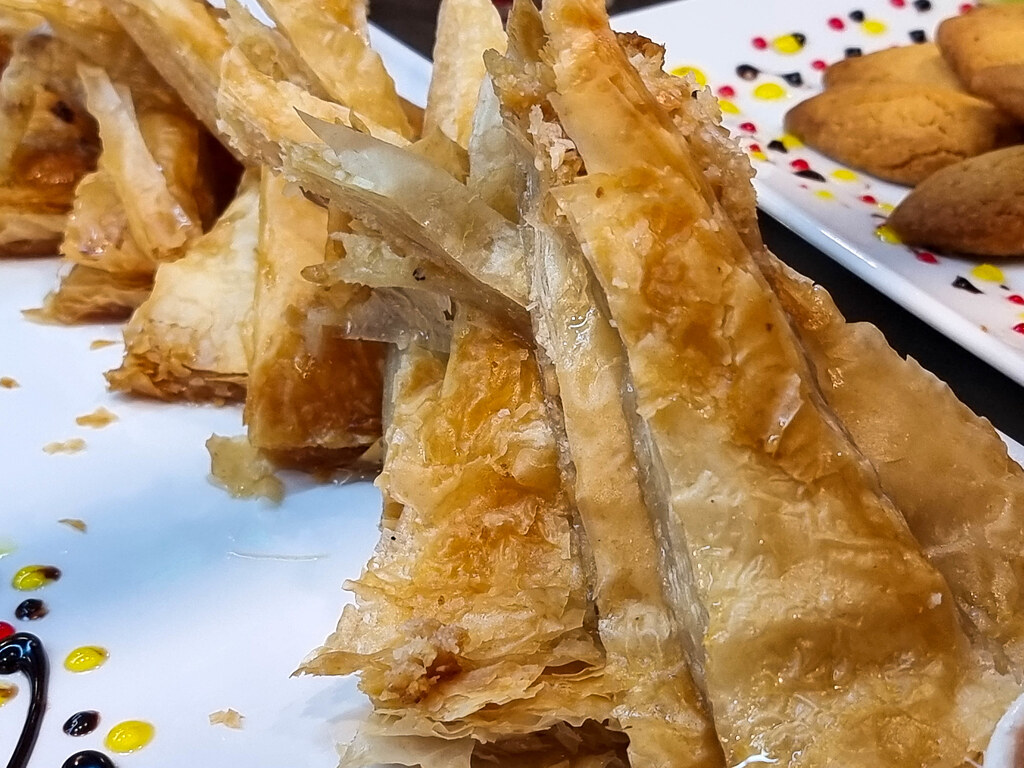 Triangular slices of baklava sat on top of each other on a white plate
