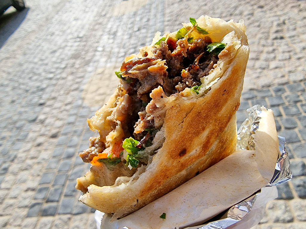 A close up photo of a shawarma, half eaten to see the meat in the interior