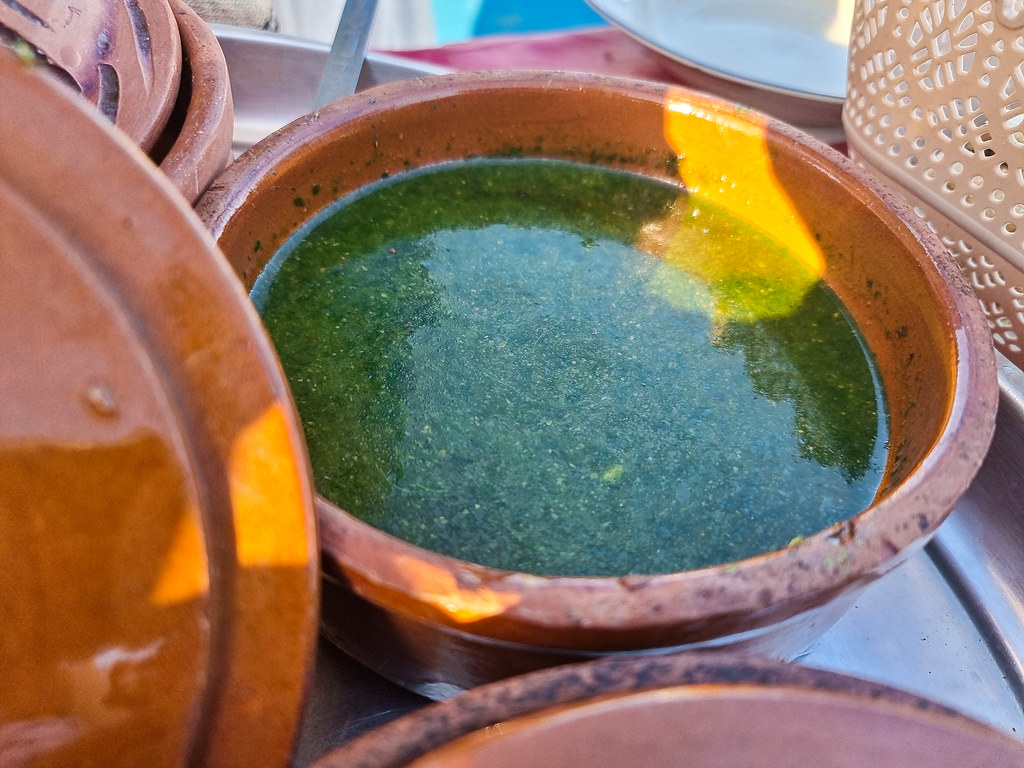 A green soup inside a brown terracotta bowl.