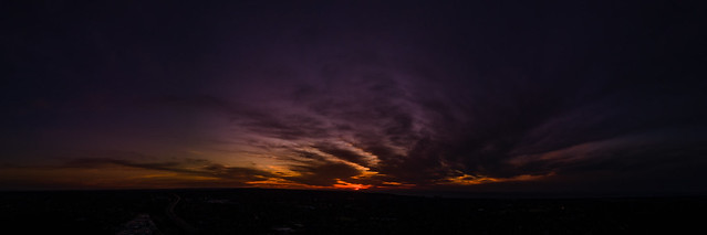 Dark wispy clouds in a deep purple sky in the afterglow of an orange sunset aerial panoramic