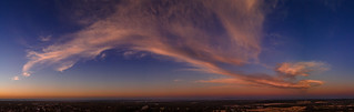 Fluffy pink clouds at sunset against a deep blue sky aerial panoramic