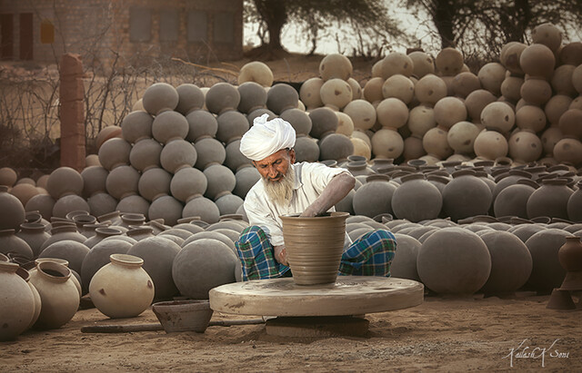 Indian potter in his traditional costume making clay pot