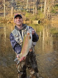 Photo of man holding a large trout in a stream