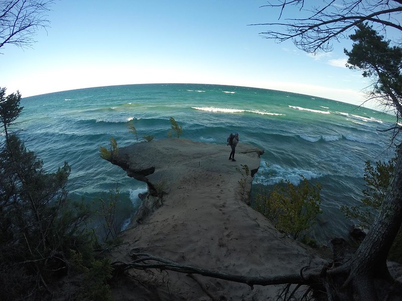 GoPro shot of Vicki standing on an awesome overhanging sandstone crag sticking out over Lake Superior on the NCT