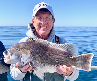 Photo of man on a boat holding up a large tautog