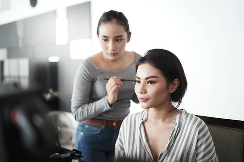 A cosmetologist helping someone with their makeup - Types of Trade Programs