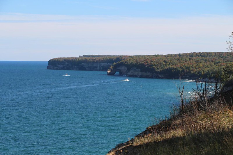Zoomed-in view east of two tour boats and the Lovers Leap natural arch from the high cliffs on the North Country Trail