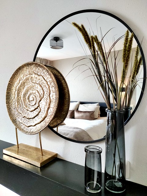 Grote ronde zwarte spiegel ornament op voet goud vaas met siergras slaapkamer hotel chique