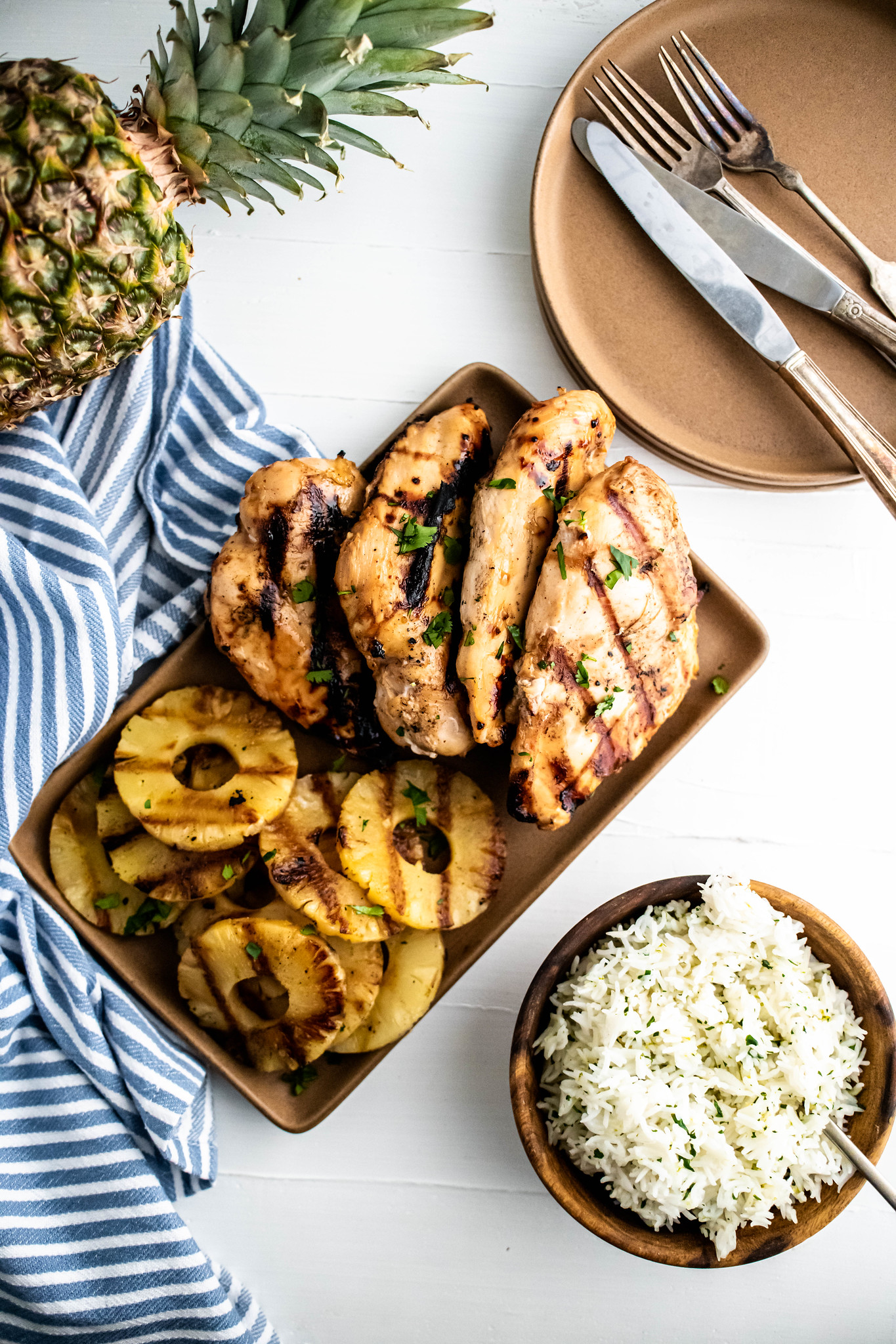 Grilled chicken and pineapple on a platter with a bowl of cilantro lime rice on the side.