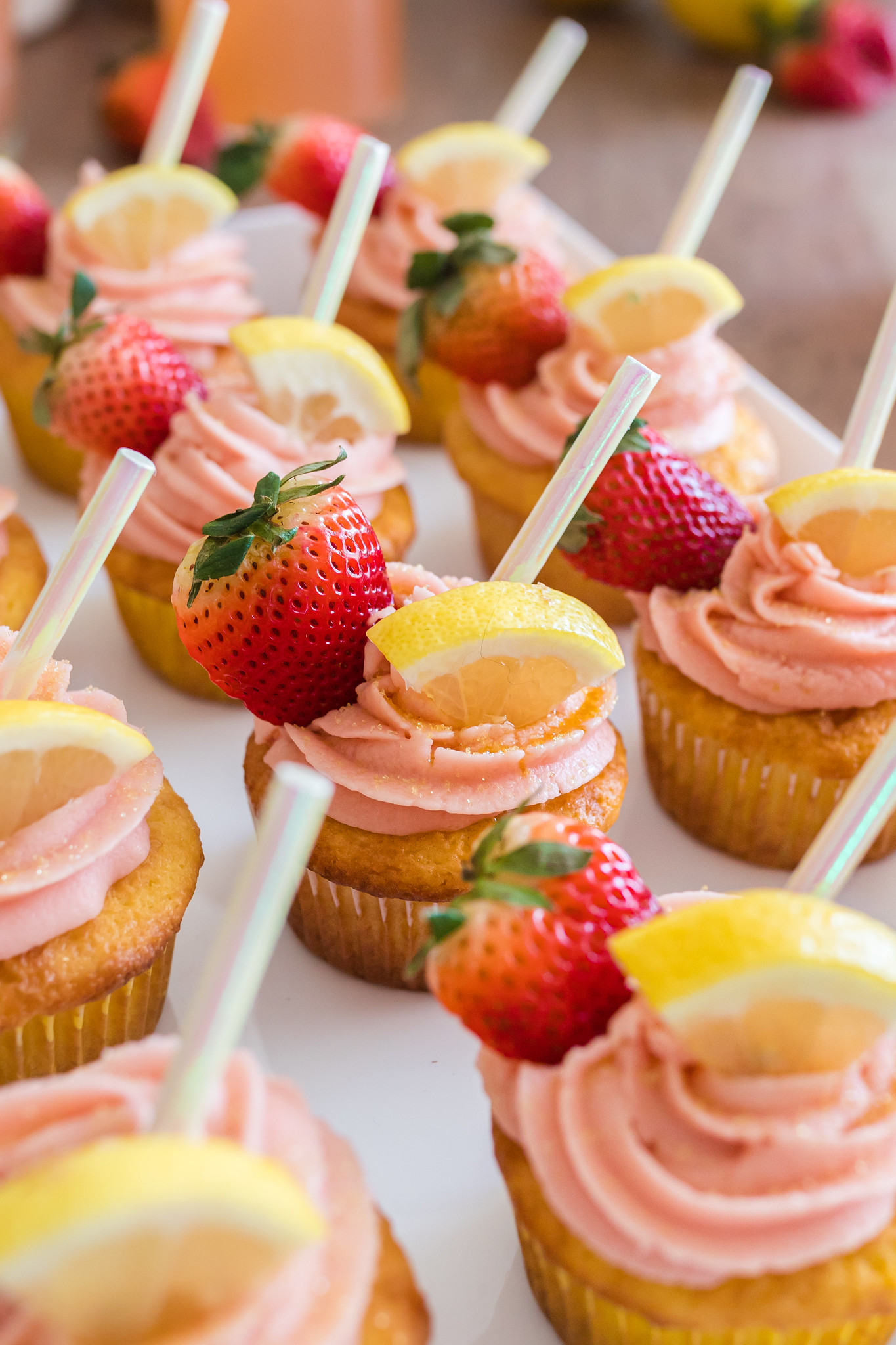 Pink lemonade cupcakes with strawberries and lemon wedges on top